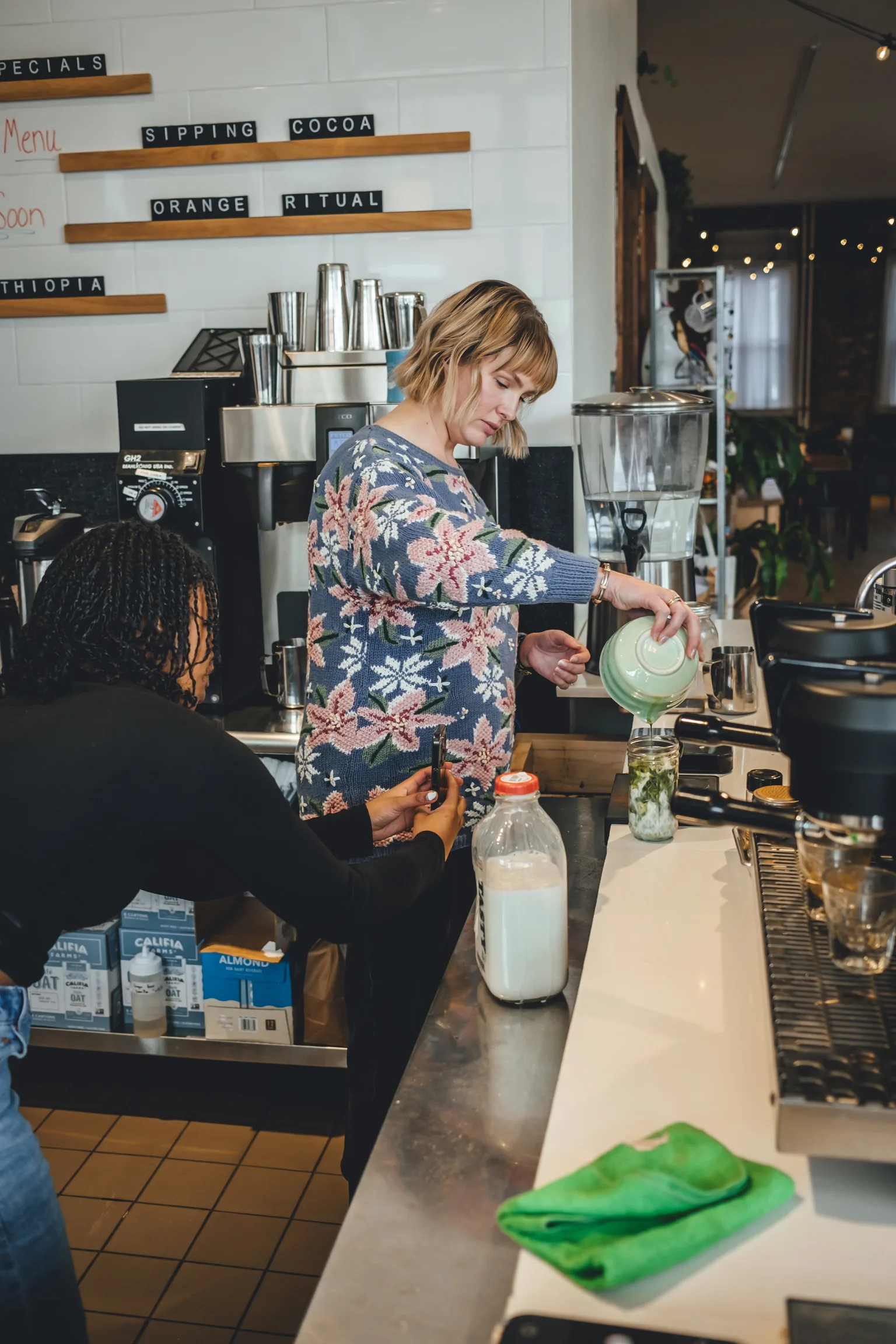 A Corner Coffee team member making a drink behind the bar