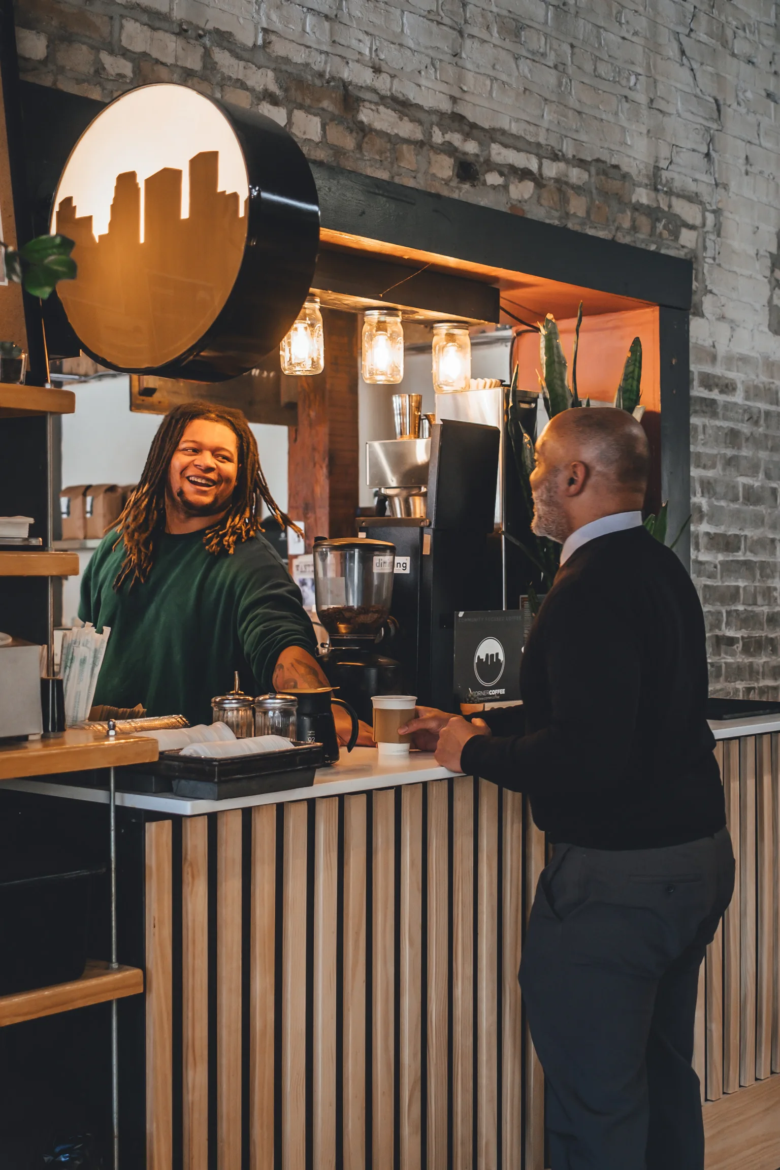 A Corner Coffee team member laughing with a guest at the counter