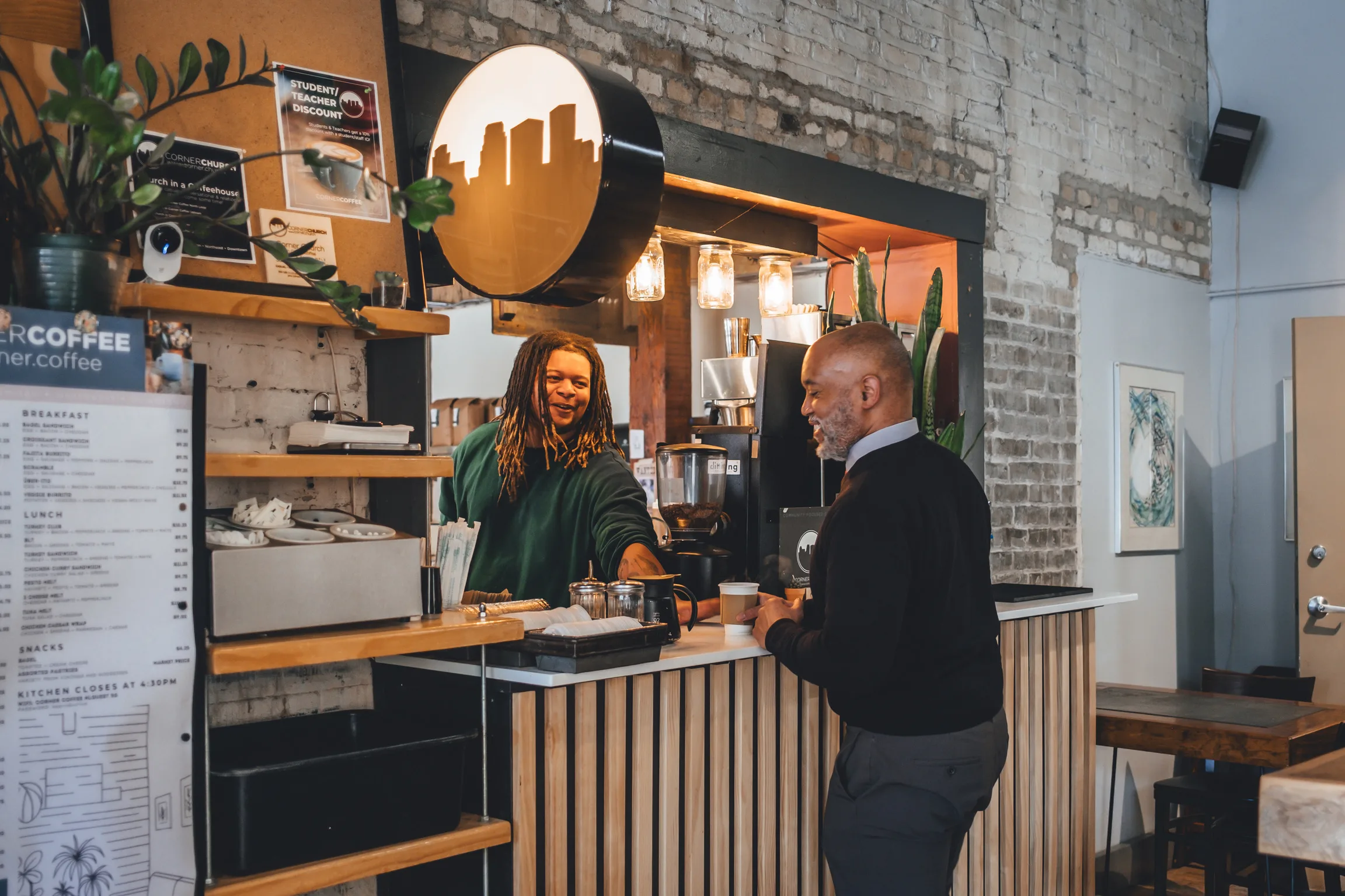 Corner Coffee North Loop barista serving a guest at the counter