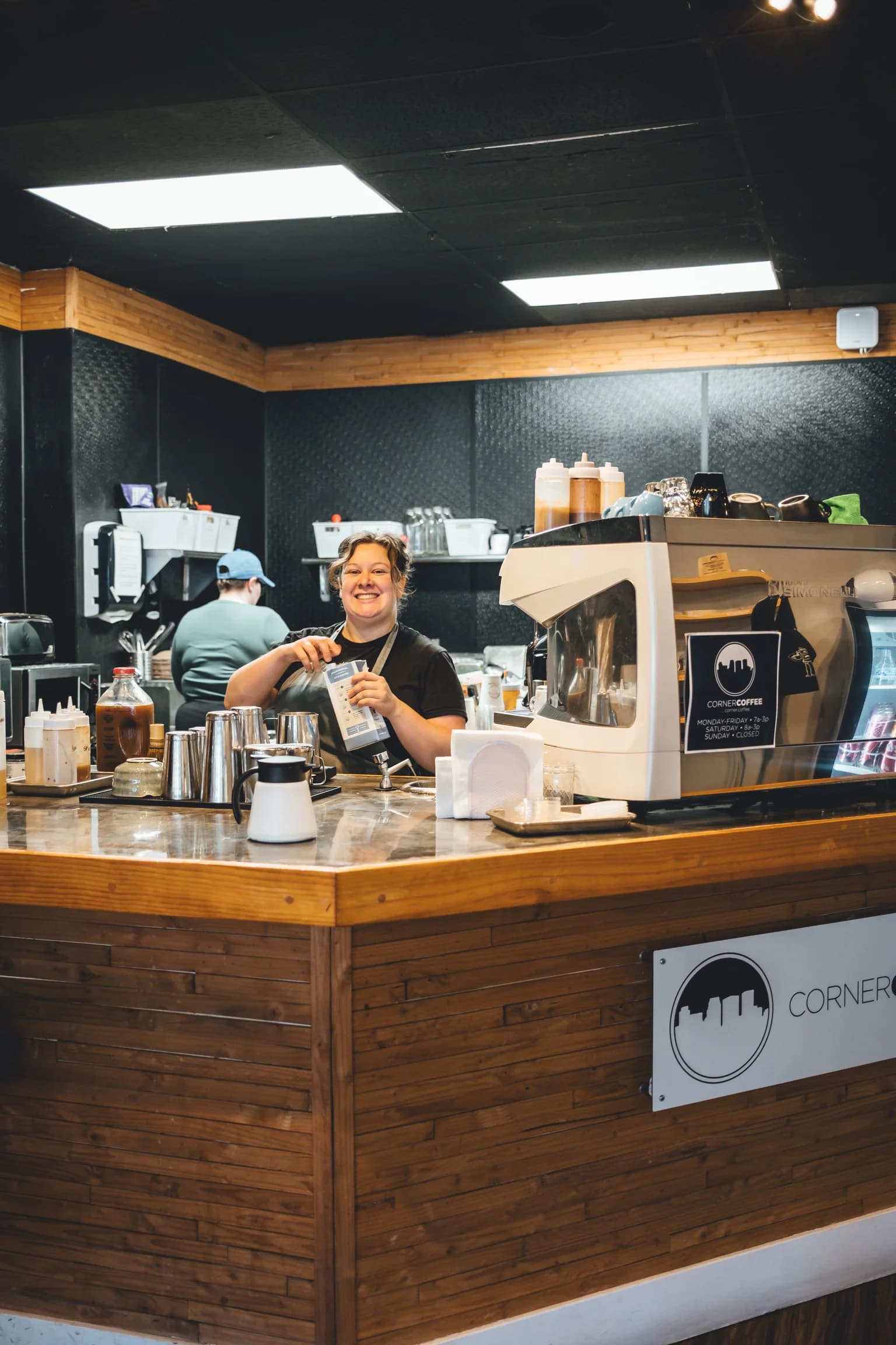 Smiling Corner Coffee Camden barista behind the wood cafe counter