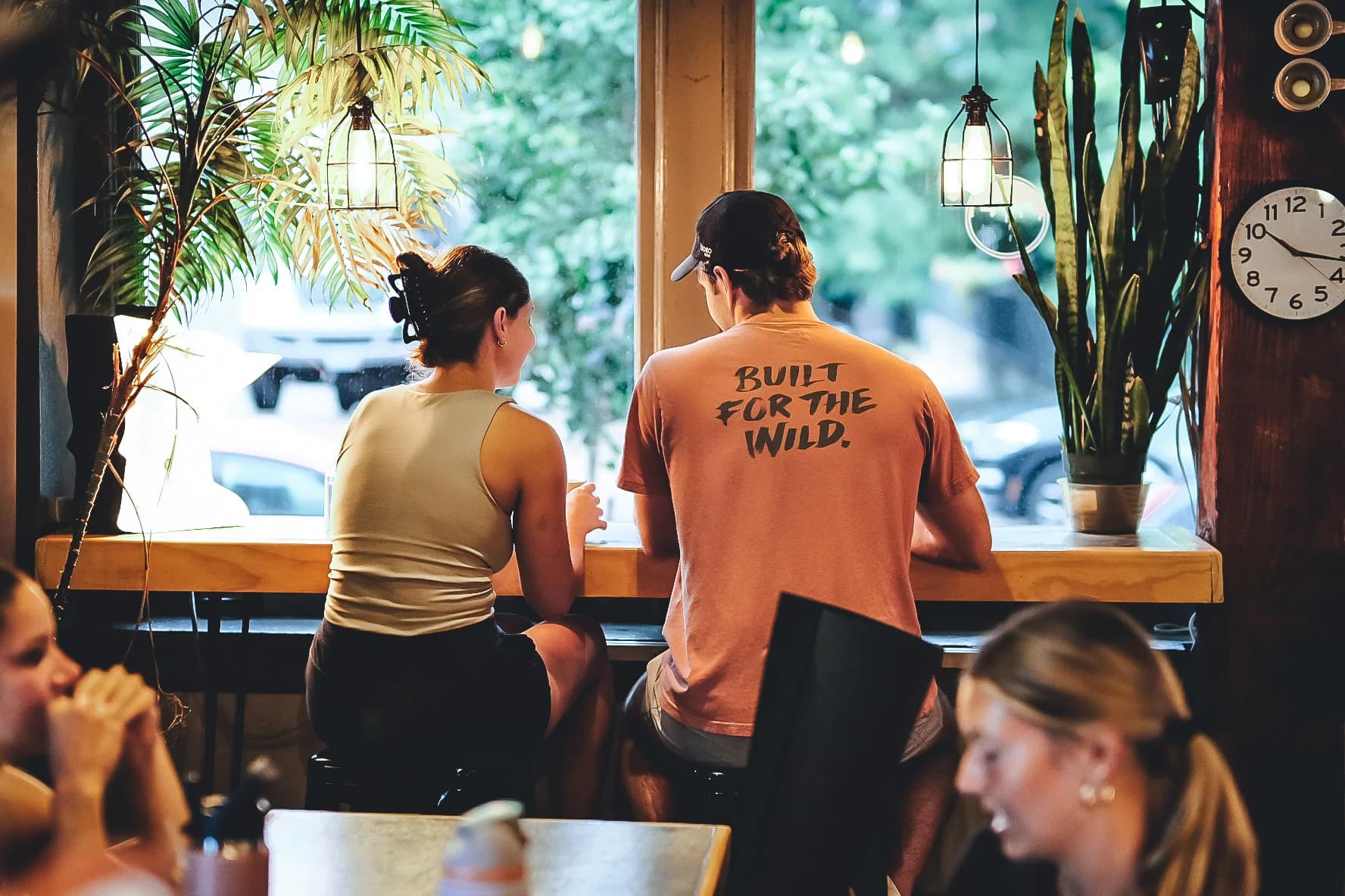 Guests sharing time together at a plant-filled Corner Coffee window bar