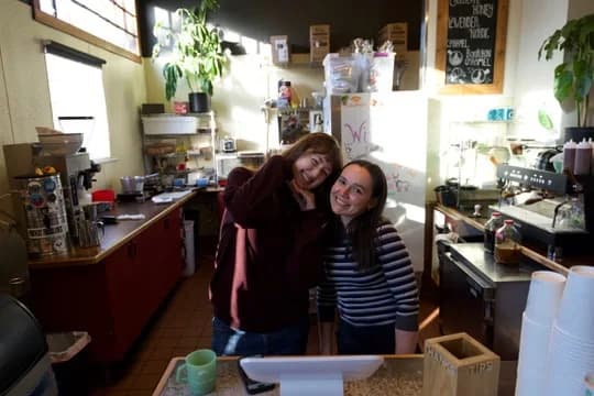 Two Corner Coffee team members smiling together behind the counter